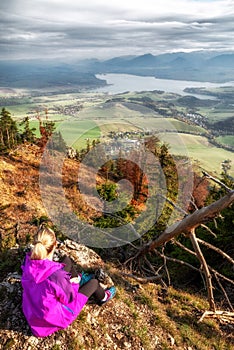 Dívka tramp sedí na vrcholu kopce a dívá se na krásnou krajinu