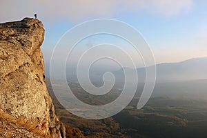 Girl hiker standing on edge of the cliff and enjoying valley vie