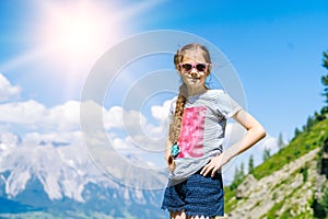 Girl hiking on beautiful summer day in alps mountains Austria, resting on rock and admire amazing view to mountain peaks