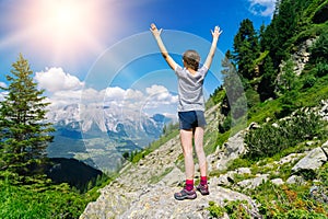 Girl hiking on beautiful summer day in alps mountains Austria, resting on rock and admire amazing view to mountain peaks