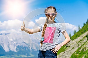 Girl hiking on beautiful summer day in alps mountains Austria, resting on rock and admire amazing view to mountain peaks