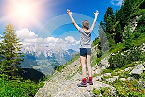 Girl hiking on beautiful summer day in alps mountains Austria, resting on rock and admire amazing view to mountain peaks. Active