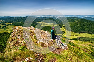 Dívka turistika sedí na vrcholu kopce Strážov s krásnou krajinou. Slovensko