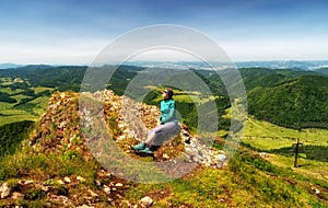 Girl hiking sitting on top of the hill Strazov with beautiful landscape. Slovakia