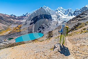 Girl hiking by stunning lake Juraucocha, San Antonio pass with view to Siula Grande peak, Huayhuash range, Huaraz, Ancash, Peru