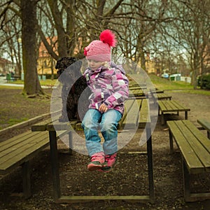 girl with his black schnauzer dog on a wooden bench