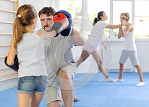 Girl hitting the focus mitts held by his boxing father