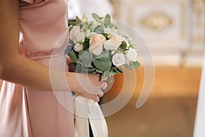 Girl hold bride`s bouquet in church. Close up