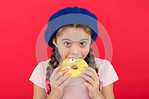 Girl hold glazed cute donut in hand red background. Kid playful girl ready to eat donut. Sweets shop and bakery concept