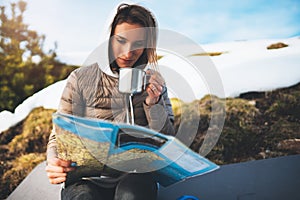 Girl hold in hands cup of drinks, relax tourist look on map, people planning trip in snow mountain, hipster enjoy on background w