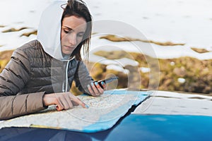 Girl hold in hands mobile phone and looking on map, hipster enjoy winter nature, relax tourist travels by auto car