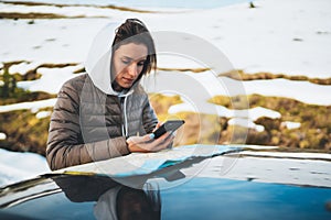 Girl hold in hands mobile phone and looking on map, hipster enjoy winter nature, relax tourist travels by auto car, people plan