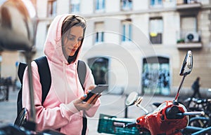 Girl hold in hands mobile phone, person type message on smartphone, tourist traveler planning trip on moto scooter, hipster enjoy