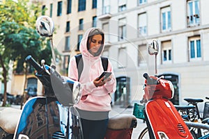 Girl hold in hands mobile phone, person type message on smartphone, tourist traveler planning trip on moto scooter, hipster enjoy