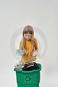 Girl hold and look at bottles from full dustbin