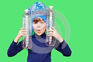 Girl hold trash bag and plastic bottle and shows interest in environmental issues isolated on green background. Child accustomed