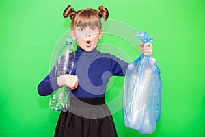 Girl hold trash bag and plastic bottle and shows interest in environmental issues isolated on green background. Child accustomed