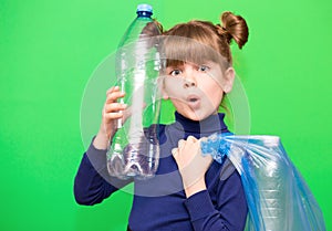 Girl hold trash bag and plastic bottle and shows interest in environmental issues isolated on green background. Child accustomed