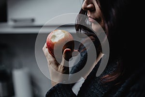 Girl holding an apple and biting a piece
