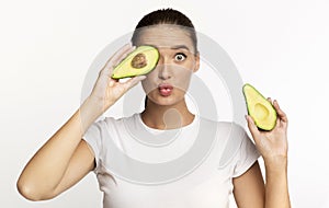 Girl Holding Avocado Halves Covering Eye Posing Over White Background