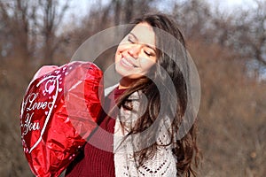 A girl holding a balloon in the form of heart.