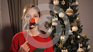 Girl holding banner with red nose and moustache