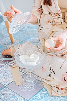 girl holding bath bombs in her hand in pink, cream and white colours on a blue background