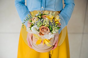 Girl holding beautiful mix flower bouquet in round box with lid