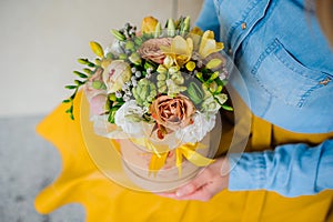 Girl holding beautiful mix flower bouquet in round box with lid