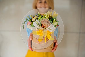 Girl holding beautiful mix flower bouquet in round box with lid