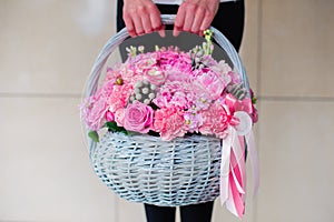 Girl holding beautiful pink bouquet of mixed flowers in basket