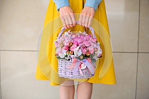 Girl holding beautiful pink bouquet of mixed flowers in basket