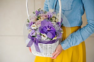 Girl holding beautiful purple bouquet of mixed flowers in basket
