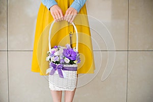 Girl holding beautiful purple bouquet of mixed flowers in basket