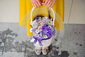 Girl holding beautiful purple bouquet of mixed flowers in basket