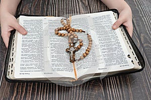 A girl holding a bible in which lies a wooden cross  background