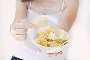 A girl holding the big potato chips bowl. Asking to eating together