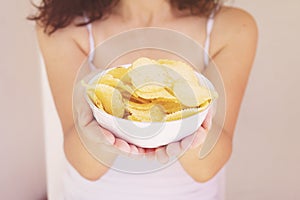 A girl holding the big potato chips bowl. Asking to eating together