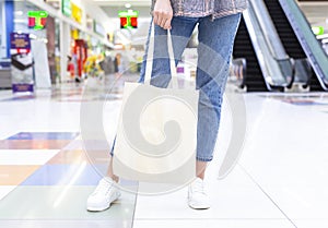 Girl holding blank cotton eco tote bag in shopping center