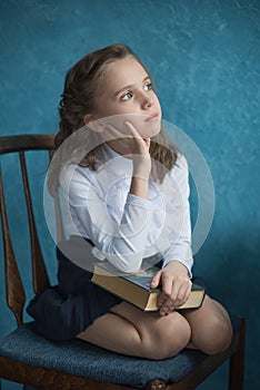 Girl holding a book on her lap and thinking