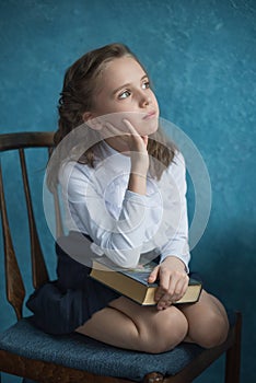 Girl holding a book on her lap and thinking photo