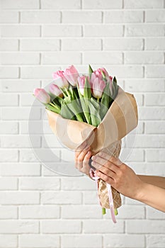 Girl holding bouquet of beautiful spring tulips near brick wall, closeup.