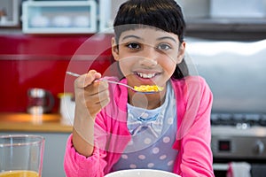 Girl holding breakfast cereal in spoon at home