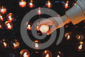 A girl is holding candle and praying near altar in church.