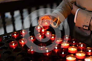 A girl is holding candle and praying near altar in church.