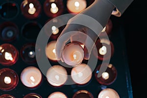 A girl is holding candle and praying near altar in church.