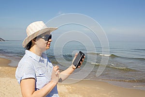 Girl holding a cellphone with sea ocean background.