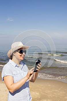 Girl holding a cellphone with sea ocean background.