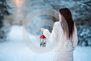 Girl holding Christmas lantern outdoors on beautiful winter snow day