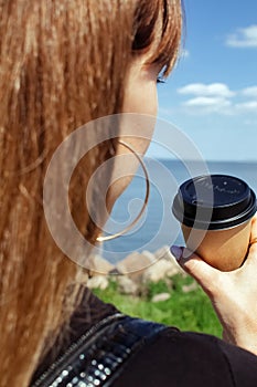 Girl holding coffee on a beautiful background. The concept of the beginning of the morning, vigor and environmental friendliness.